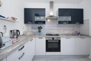 een keuken met witte kasten en zwarte apparaten bij Apartment Villa DD in Supetar