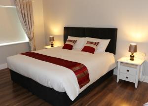 1 dormitorio con 1 cama grande con almohadas rojas en Laneside Haven - 5 Minutes from Castleblayney - Accessible, Gated with Patio, Garden and Gym!, en Monaghan