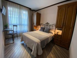 a bedroom with a bed and a desk and a window at Hotel Los Molinos in Llanes