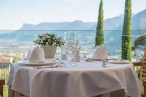 un tavolo con una tovaglia bianca e bicchieri da vino di Hotel Patrizia a Tirolo