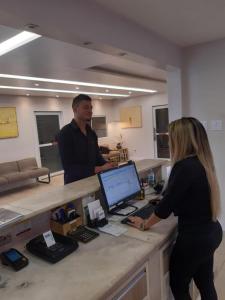 Ein Mann und eine Frau stehen an einem Schreibtisch mit einem Computer. in der Unterkunft Atalanta Hotel in Macapá