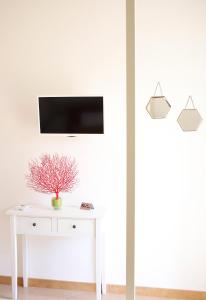 un salon avec une table blanche et une télévision au mur dans l'établissement Casa Tarantino Charming apartments, à Capri