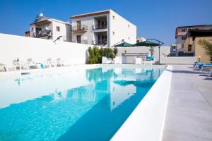 a swimming pool with blue water in front of a building at Villa Concettina in Capo dʼOrlando