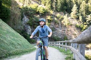 Ein Mann, der ein Fahrrad auf einer unbefestigten Straße reitet in der Unterkunft Hotel Patrizia in Dorf Tirol
