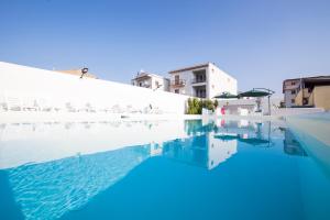 a swimming pool with blue water and white buildings at Villa Concettina in Capo dʼOrlando