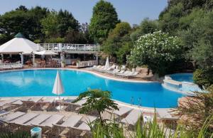einen Pool mit Stühlen und Sonnenschirmen in einem Resort in der Unterkunft Hotel Villa Pigalle in Tezze sul Brenta