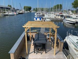 a wooden dock with a table and chairs on the water at Magnifique bateau maison in Ouistreham