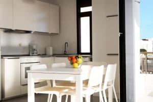 a white kitchen with a white table and white chairs at Arinaga Colors, tu casa en la playa in Arinaga