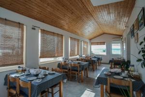 a dining room with tables and chairs and windows at House Zaca in Zavala