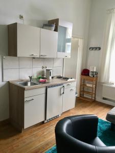 uma cozinha com armários brancos, um lavatório e um sofá em Apartment Schloss Benrath em Greifswald