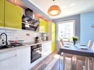 a kitchen with a dining table and yellow cabinets at Leśne Tarasy apartament Krabik Dziwnówek in Dziwnówek +8 photos