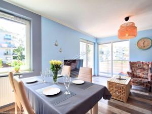 a dining room with a table with a blue wall at Leśne Tarasy apartament Krabik Dziwnówek in Dziwnówek