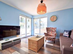 a living room with a couch and a clock on the wall at Leśne Tarasy apartament Krabik Dziwnówek in Dziwnówek