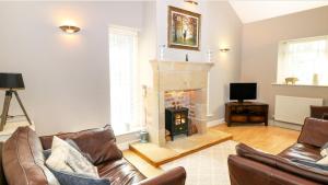 a living room with a fireplace and leather furniture at Unicorn Cottage in Bakewell