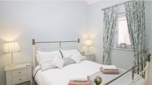 a bedroom with a white bed and a window at Unicorn Cottage in Bakewell