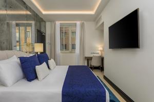a bedroom with a large bed and a flat screen tv at Room Mate Collection Filippo, Rome-Fontana di Trevi in Rome +34 photos