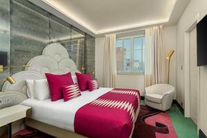 a bedroom with a large bed with red and white pillows at Room Mate Collection Filippo, Rome-Fontana di Trevi in Rome