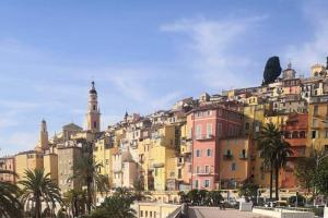 a view of a city with buildings and palm trees at Vue mer port de garavan in Menton