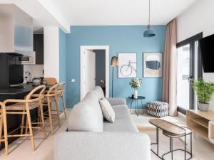 a living room with a white couch and a blue wall at Limehome Sevilla Calle Torcuato Luca de Tena - Digital Access in Seville