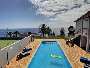 una piscina con 2 tumbonas en la parte lateral de una casa en Villa Prainha by LovelyStay, en Caniçal