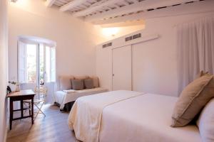 a white bedroom with two beds and a window at CASA FILOMENA in Barcelona