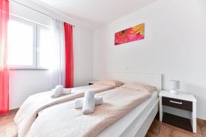 a white bedroom with a bed and a window at Apartments Villa Visnjik in Zadar