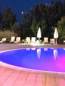 a swimming pool at night with chairs and umbrellas at Agriturismo l'Ovile in Latina