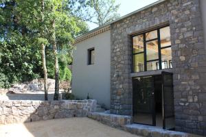 een stenen huis met een grote glazen deur bij Gîtes Domaine de la Barnerie in Saint Alban Auriolles