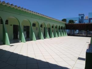 a green building with arches and a tiled courtyard at Pousada Difusão Cultural in Praia Grande