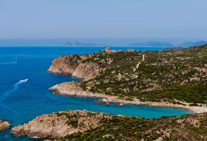 an island in the ocean with a house on it at Faro Capo Spartivento in Chia