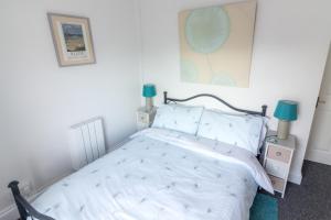 una camera da letto con un letto con lenzuola bianche e lampade blu di Utopia Apartments a Perranporth