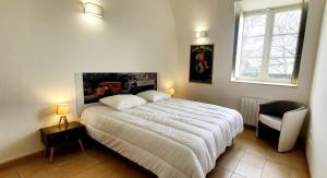 a bedroom with a large white bed and a chair at Appartement "POULAIN" en Centre-ville linge inclus in Blois