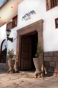 a entrance to a hotel with two potted plants at Mamasara Cusco in Cusco