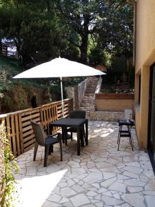 un tavolo con sedie e un ombrellone su un patio di Chez Sylvie et Amador a Las Illas