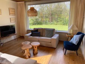 ein Wohnzimmer mit einem Sofa und einem Tisch in der Unterkunft Family bungalow with garden for 6-8 people in Cadzand