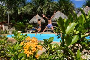 two people jumping into a swimming pool at Encantes do Nordeste in Barreirinhas