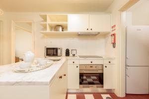 uma cozinha com armários brancos e um frigorífico branco em YOUROPO - Flores no Porto