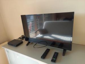 a computer monitor sitting on a desk with two remote controls at Appartement vlakbij zee en duinen in Bredene