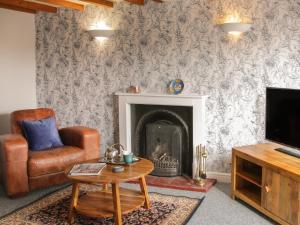 a living room with a chair and a fireplace at 1 Royal Oak Cottages in Shrewsbury