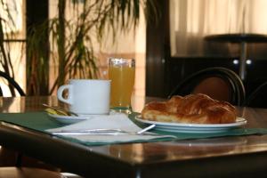 a table with a plate of bread and a cup of orange juice at Hotel Austria 76 in Puerto de Sagunto