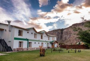 ein weißes Gebäude mit einem Berg im Hintergrund in der Unterkunft Hostel Pioneros del Valle in El Chalten