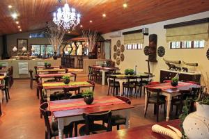 a restaurant with tables and chairs and a chandelier at Emdoneni Lodge in Hluhluwe