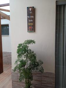 una pianta seduta accanto a un muro con un cartello di Suítes da Rô - hospedaria familiar diária e temporada a Varginha