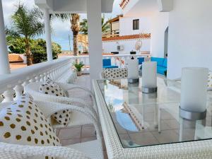 a balcony with white chairs and a glass table at Villa Carolina with private pool in Salobre