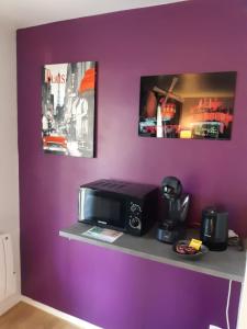 un mur violet avec une étagère et un four micro-ondes dans l'établissement Briget Apartment, à Chessy