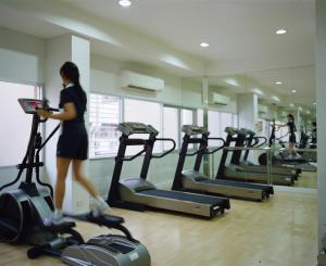 Una mujer caminando en una cinta de correr en un gimnasio en Rangsit Apartment I, en Ban Talat Rangsit
