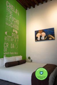 1 dormitorio con 1 cama con pared verde en Kuku Ruku Hotel, en Querétaro