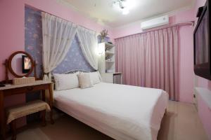 um quarto com uma cama branca e uma parede rosa em RaRa Stay em Taichung