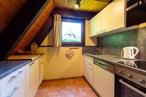 eine Küche mit weißen Schränken und einem Fenster in der Unterkunft Ferienwohnpark Immenstaad am Bodensee Nurdachhaus Typ 8 NDT 036 in Immenstaad am Bodensee + 9 Fotos