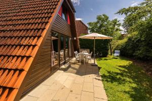 eine Terrasse mit einem Sonnenschirm neben einem Haus in der Unterkunft Ferienwohnpark Immenstaad am Bodensee Nurdachhaus Typ 8 NDT 036 in Immenstaad am Bodensee